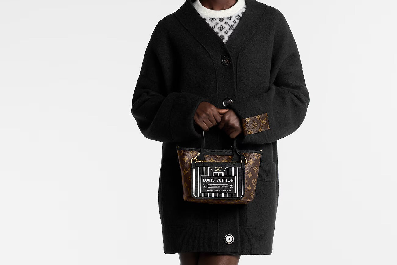 Person holding a Louis Vuitton handbag against a white background