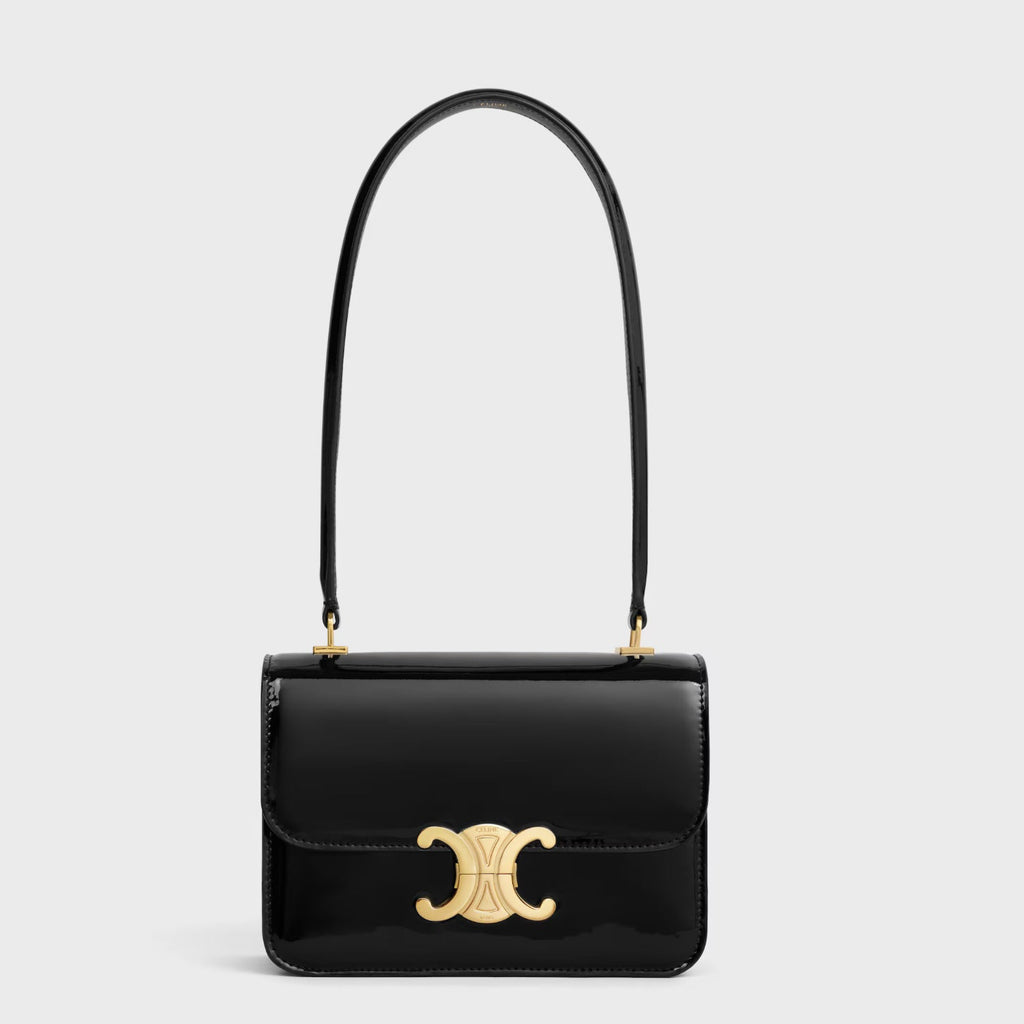 Black handbag with gold clasp on a light gray background